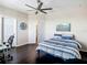 Bedroom featuring wood-look floors, ceiling fan, and queen-sized bed with striped bedding at 4744 Wandering Way, Wesley Chapel, FL 33544
