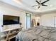Main bedroom showcasing a tray ceiling, mounted TV, wood floors and access to a private balcony at 4744 Wandering Way, Wesley Chapel, FL 33544