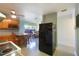 Eat-in kitchen featuring wood cabinets, tile flooring, and an adjacent living area with a black fridge at 4932 Murray Hill Dr, Tampa, FL 33615