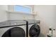 Modern laundry room with front-load washer and dryer, and convenient shelving at 5917 Cat Claw Ln, Bradenton, FL 34210