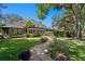 Expansive backyard showcasing the home's exterior, lush lawn, and stone pathway at 6352 W Maclaurin Dr, Tampa, FL 33647