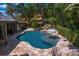 Aerial view of a backyard pool featuring a waterfall, in-pool umbrella, and lush tropical landscaping at 6352 W Maclaurin Dr, Tampa, FL 33647