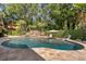 Backyard pool with a rock waterfall and in-pool umbrella surrounded by manicured landscaping at 6352 W Maclaurin Dr, Tampa, FL 33647