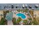 Aerial view of a shared kidney-shaped pool, pool house and palm trees near a canal with boat docks at 6414 Sunset Bay Cir, Apollo Beach, FL 33572
