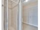 Close-up of a glass shower with neutral tile and access to a large walk-in closet with shelving at 6414 Sunset Bay Cir, Apollo Beach, FL 33572