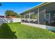 A screened lanai sits to the right of a spacious backyard with green grass and a white fence at 7690 91St St, Seminole, FL 33777