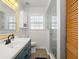 Bright bathroom featuring a glass shower, shuttered window, vanity with storage, and wood look floors at 7690 91St St, Seminole, FL 33777