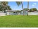 Charming blue single-story home with a green lawn and inviting yellow door at 7690 91St St, Seminole, FL 33777