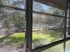 Serene outdoor view through screened windows, showcasing green space and mature trees at 8320 112Th St # 206, Seminole, FL 33772