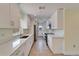 Well-lit galley kitchen featuring new stainless appliances, stone countertops and bright white cabinetry at 8702 Driftwood Dr, Tampa, FL 33615