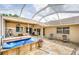 A covered back patio featuring a hot tub with stone flooring and outdoor ceiling fans at 9229 Dayflower Dr, Tampa, FL 33647