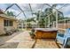 Screened-in back patio with stone flooring, chairs, potted plants, and a hot tub at 9229 Dayflower Dr, Tampa, FL 33647