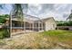 A view of the backyard featuring the screened-in back patio and lawn at 9229 Dayflower Dr, Tampa, FL 33647