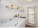 Bright laundry room featuring a washer, dryer, shelves, and a door to the outside at 9229 Dayflower Dr, Tampa, FL 33647