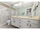 Well-lit bathroom with double sinks, white cabinetry, and a glass-enclosed shower for a clean and functional space at 11026 Austin Ct, New Port Richey, FL 34654