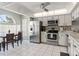 Open kitchen showcasing white cabinets, stainless steel appliances, and tile flooring at 11026 Austin Ct, New Port Richey, FL 34654