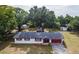 Charming single-story home featuring white exterior, red trim, mature trees, and well-maintained landscaping at 12213 Floral Ln, Thonotosassa, FL 33592