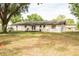 Rear exterior showcasing the yard and home's layout featuring mature trees, grass and small deck at 12213 Floral Ln, Thonotosassa, FL 33592