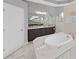 Luxurious bathroom with a soaking tub, dual vanity sinks, and elegant marble-style tile at 1312 Fishing Lake Dr, Odessa, FL 33556