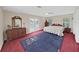 Large main bedroom with red carpet, blue rug, dresser, and double doors to backyard at 1312 Fishing Lake Dr, Odessa, FL 33556