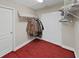 Walk-in closet with red carpet, bi-fold doors and hanging clothes with shelving above at 1312 Fishing Lake Dr, Odessa, FL 33556