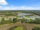 Panoramic aerial view of a serene community featuring lush green spaces, a tranquil pond, and well-spaced homes at 15615 Serengeti Blvd, Spring Hill, FL 34610