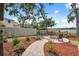 Backyard with circular stone fire pit surrounded by chairs and colorful landscaping, with a view of the lake at 15615 Serengeti Blvd, Spring Hill, FL 34610