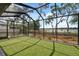 Backyard with screened-in patio and wrought-iron fence with a view of the lake at 15615 Serengeti Blvd, Spring Hill, FL 34610