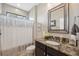 Bathroom features a granite counter, decorative mirror, and tiled shower with silver accents at 15615 Serengeti Blvd, Spring Hill, FL 34610