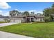 Home showcasing a well-maintained lawn, a three-car garage, and colorful front garden with seating at 15615 Serengeti Blvd, Spring Hill, FL 34610