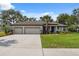 Charming home featuring a long driveway, three-car garage, and well-maintained lawn and landscaping at 15615 Serengeti Blvd, Spring Hill, FL 34610