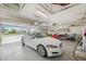 Garage showcasing a white Jaguar, overhead storage racks, and epoxy-coated floors at 15615 Serengeti Blvd, Spring Hill, FL 34610