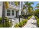 Townhome exterior with black metal fence, green shrubs, stone walkway, and white siding on a sunny day at 206 S Tampania Ave # 4, Tampa, FL 33609