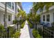A walkway in a townhouse community shows a shared walkway, green bushes, black metal fence, and bright blue sky at 206 S Tampania Ave # 4, Tampa, FL 33609