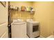 Well-lit laundry room features modern washer and dryer units, storage shelving, and a convenient door at 3000 Jacob Crossing Ln, Holiday, FL 34691