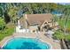 Community pool with tables and chairs for relaxing, alongside a building with mature trees in the background at 3276 Hilary Cir, Palm Harbor, FL 34684
