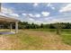 A scenic backyard featuring a covered patio, lush green lawn, and a serene pond surrounded by mature trees at 33176 Whisper Pointe Dr, Wesley Chapel, FL 33545