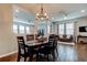 Open-concept dining room featuring a modern chandelier, hardwood flooring, and adjoined living space at 33176 Whisper Pointe Dr, Wesley Chapel, FL 33545