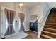 Inviting entryway with a wooden staircase, stylish light fixture, and decorative accents at 33176 Whisper Pointe Dr, Wesley Chapel, FL 33545