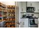 Modern kitchen featuring walk-in pantry with organized shelving, stainless steel appliances, and white cabinetry at 33176 Whisper Pointe Dr, Wesley Chapel, FL 33545
