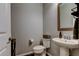 Quaint powder room with a pedestal sink, toilet, and decorative mirror, perfect for guests at 33176 Whisper Pointe Dr, Wesley Chapel, FL 33545