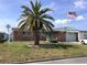 Charming brick home featuring a lush front lawn, vibrant palm tree, and an American flag displayed proudly at 3850 Sablewood Dr, Holiday, FL 34691