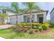 Attractive home featuring a two-car garage, stone accents, colorful bushes, and well-kept landscaping at 5059 Bromeliad Ave, Wimauma, FL 33598