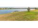 Picturesque lake view with a grassy shoreline in a residential community on a clear, sunny day at 5059 Bromeliad Ave, Wimauma, FL 33598