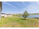 Scenic lake view from the backyard with lush green grass and community homes in the background at 5059 Bromeliad Ave, Wimauma, FL 33598