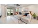 Bright living room features a sliding glass door to the lanai, plush sectional sofa, and neutral tile flooring at 5059 Bromeliad Ave, Wimauma, FL 33598