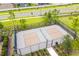 Aerial view of a fenced pickleball court in a sunny, well-maintained community with lovely landscaping surrounding the court at 5059 Bromeliad Ave, Wimauma, FL 33598
