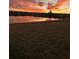 Scenic sunset reflecting over a lake with waterfront houses in the background and green space in the foreground at 5059 Bromeliad Ave, Wimauma, FL 33598