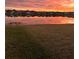 Beautiful sunset reflecting over a lake with waterfront houses in the background and green space in the foreground at 5059 Bromeliad Ave, Wimauma, FL 33598