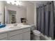 Bathroom features a white vanity, large mirror, toilet, and a shower with a grey shower curtain at 6225 Scarlet Darter Way, Tampa, FL 33625